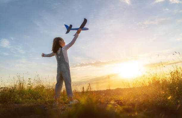 Happy kid with toy plane is playing at sunset.