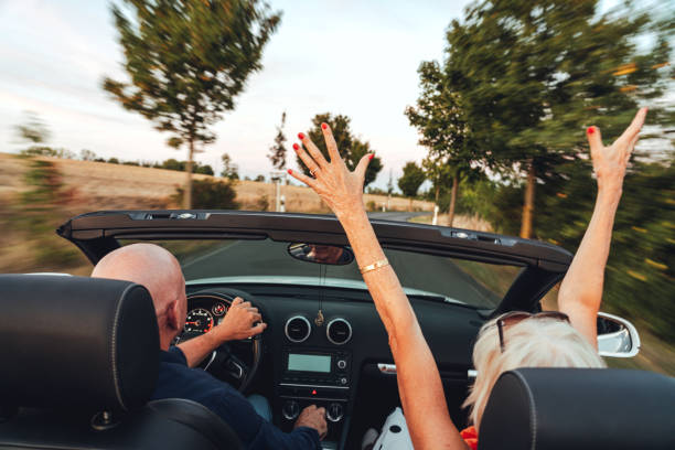 coppia di anziani che guidano nella loro auto e si divertono nel viaggio su strada - driving women rear view sitting foto e immagini stock