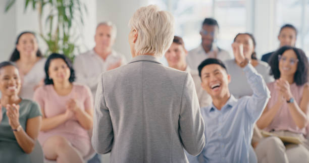 istock Wow, motivation and celebration with a crowd or audience cheering for a leader, manager or CEO in a meeting at work. Training, coaching and success with a woman boss talking to staff in a conference 1423007235