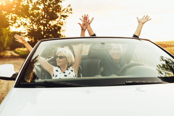 istock Happy senior couple having fun driving on convertible car 1423007724