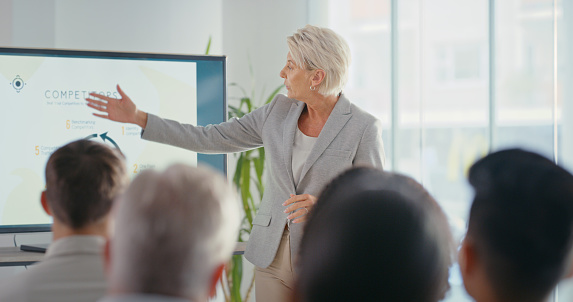 Business woman giving a presentation at a corporate conference in a modern office building. Global company manager doing leadership, development and management training with employees at a workshop.