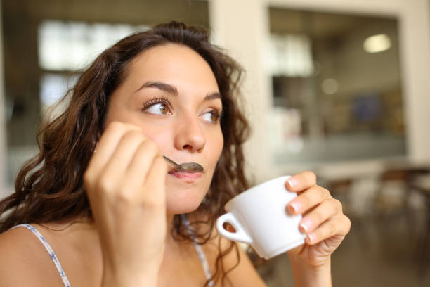 istock Woman drinking coffee using spoon in a bar 1423008417