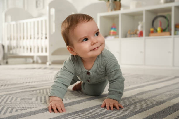 Cute baby crawling on floor at home stock photo