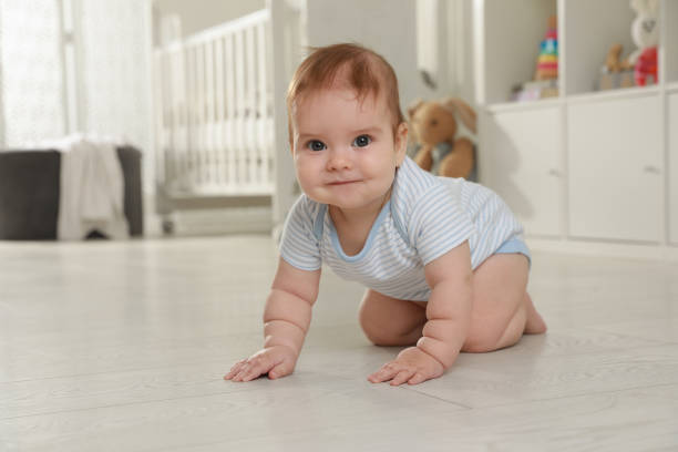 istock Cute baby crawling on floor at home 1423008551