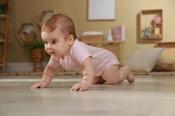 istock Cute baby crawling on floor at home 1423008604