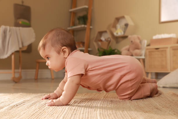 istock Cute baby crawling on floor at home 1423009353