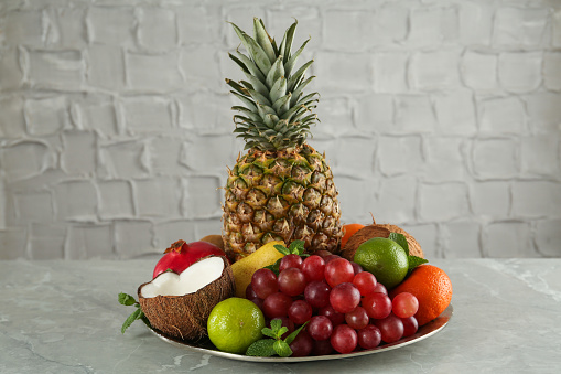 Plate with different ripe fruits on grey table