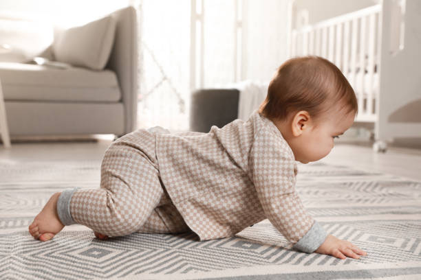 istock Cute baby crawling on floor at home 1423009489