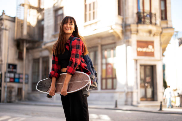 istock Young urban woman with skateboard outside 1423009593