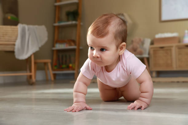 istock Cute baby crawling on floor at home 1423009744