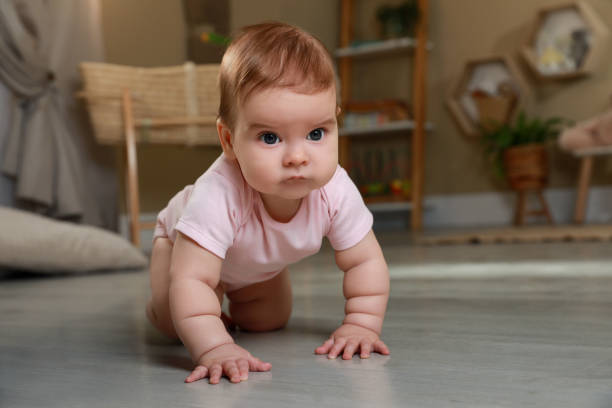 istock Cute baby crawling on floor at home 1423009745