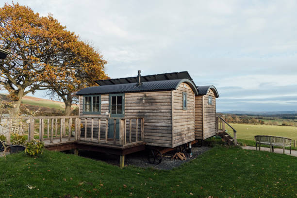 A shot of luxury wooden huts overlooking a grass field at a glamping site in Alnwick, Northumberland.