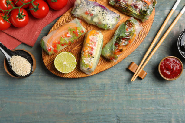 istock Many different delicious rolls wrapped in rice paper on blue wooden table, flat lay. Space for text 1423013034