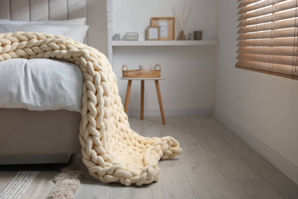 istock Soft chunky knit blanket on bed in stylish room interior 1423013142