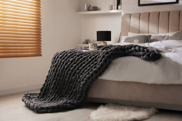 istock Soft chunky knit blanket on bed in stylish room interior 1423013215