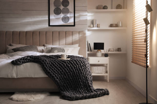 istock Soft chunky knit blanket on bed in stylish room interior 1423013518