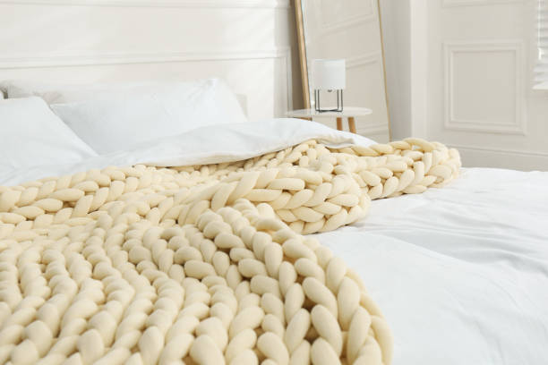 istock Soft chunky knit blanket on bed in light room 1423013876