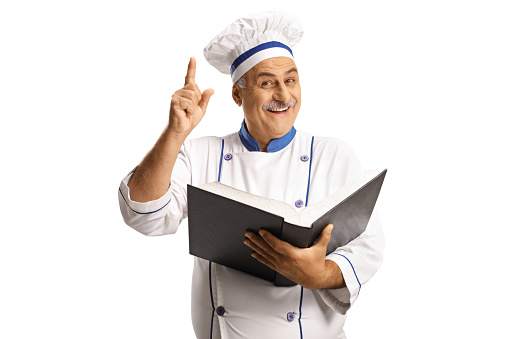 Mature male chef holding a cook book isolated on white background