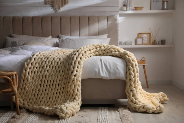istock Soft chunky knit blanket on bed in stylish room interior 1423014219