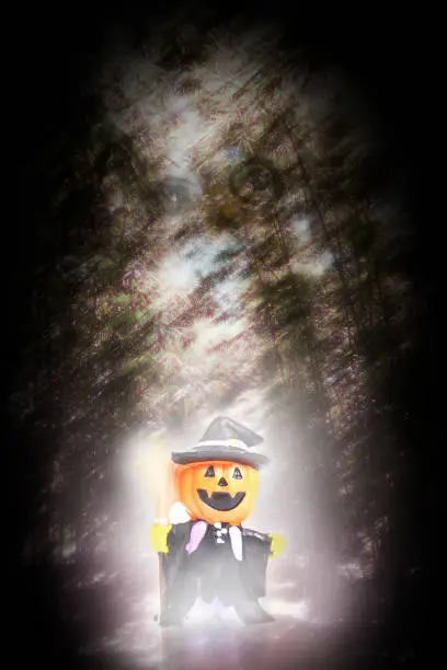 Pumpkin-headed witch doll appears in dark and terrifying forest on Halloween night.