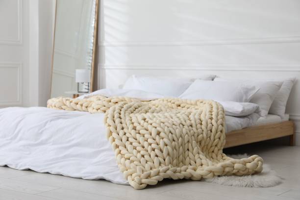 istock Soft chunky knit blanket on bed in stylish room interior 1423015510