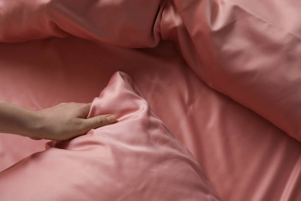 mujer haciendo la cama con hermosas sábanas de seda rosa, vista de cerca - seda fotografías e imágenes de stock