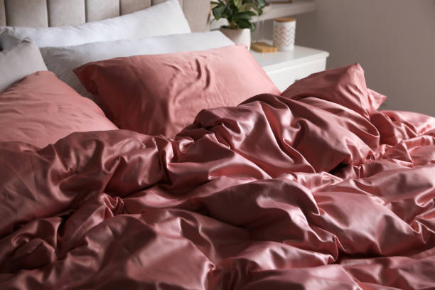 Bed with beautiful silk linens indoors, closeup