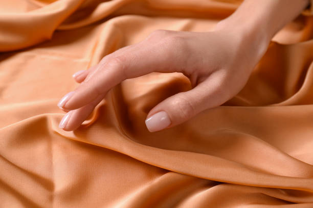 istock Woman touching soft orange fabric, closeup view 1423015862