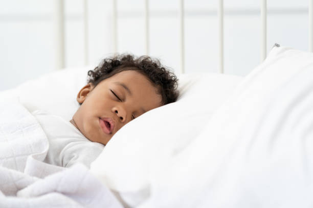 istock black african american baby sleeping on a white mattress. 1423015904