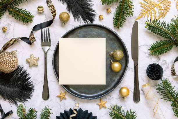 istock Black and golden Christmas Table setting with a card, ornaments and fir tree branches. Mockup 1423015934