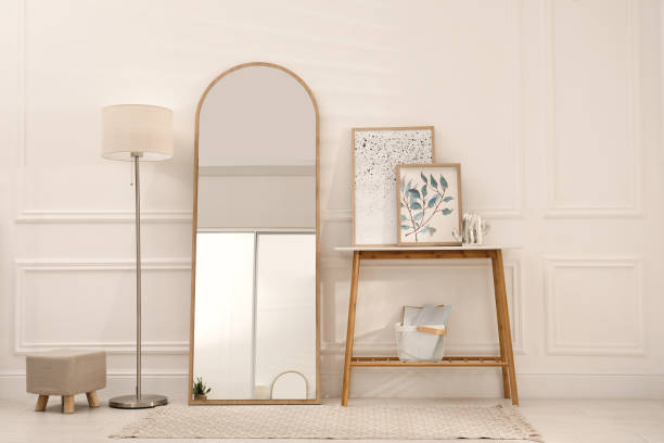 istock Beautiful mirror, console table and lamp near white wall indoors. Interior design 1423016177