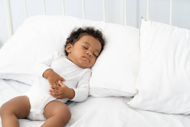 istock black african american baby sleeping on a white mattress. 1423016504
