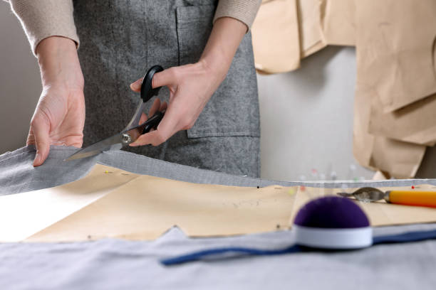 istock Tailor cutting fabric with scissors at table in atelier, closeup 1423016828