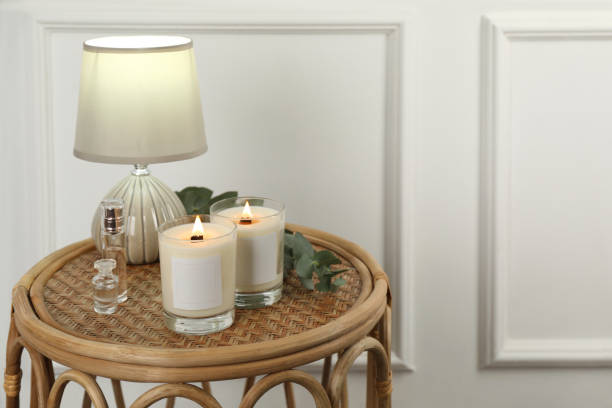 istock Burning soy candles, lamp, perfumes and eucalyptus branch on wicker table indoors. Space for text 1423017364