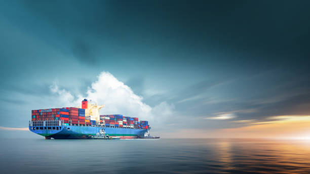 Container cargo ship in ocean at sunset dramatic sky background with copy space, Nautical vessel and sea freight shipping, International global business logistics transportation import export concept stock photo