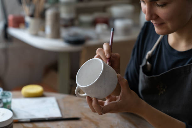istock Happy craftswoman enjoys creating clay dish for decorating kitchen making sketch with pencil 1423019756
