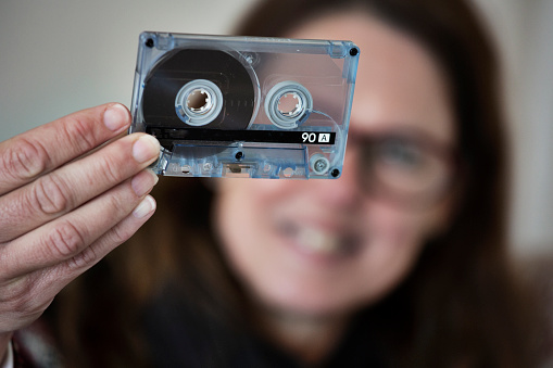 A woman holds an audio cassette tape