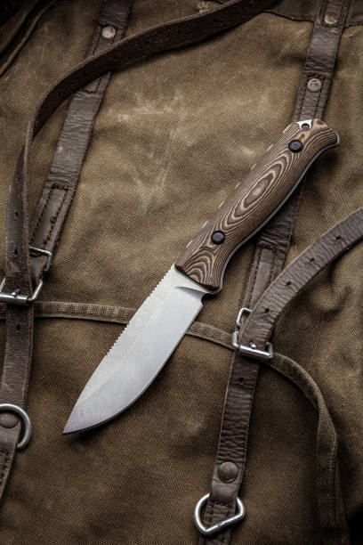 istock A hunting knife with a wooden handle on a khaki canvas backpack. Weapons for self-defense and survival. 1423020472