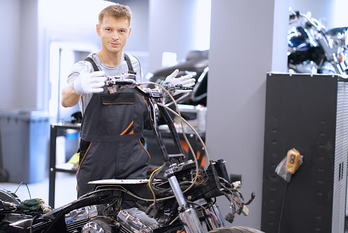 Auto mechanic checks technical condition of motorcycle in workshop. Vehicle service station services concept