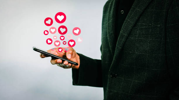 istock Hand holding mobile phone is sending heart emoticon. 1423024671