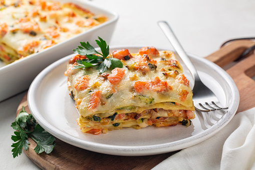 Close up of Lasagna with salmon fish, zucchini, bechamel sauce, parmesan cheese and leek.  Baked in oven italian pasta made of flat sheets.