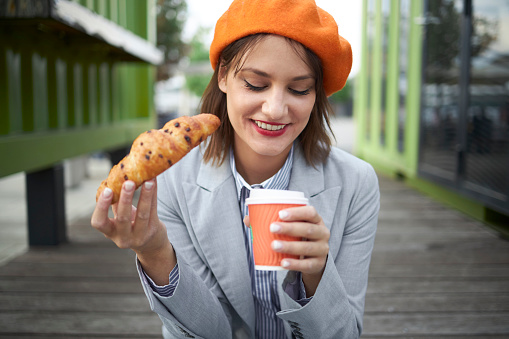 Woman bite croissant outdoor bar breakfast