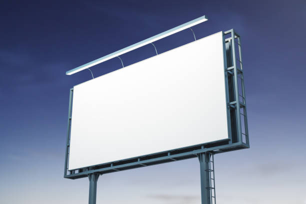 istock Blank white billboard on blue sky background at night, perspective view. Mockup, advertising concept 1423028340