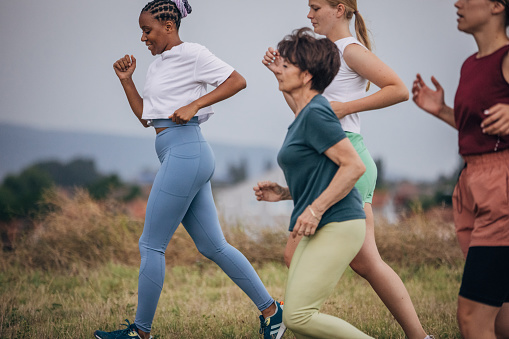 Diverse group of women jogging together on a summer day on a meadow in nature.