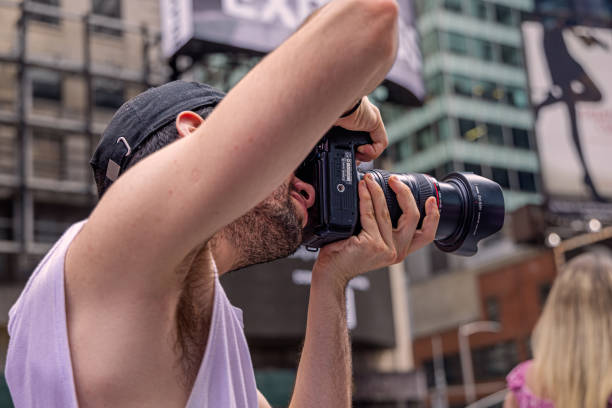 Times Square, Manhattan, New York, NY, USA - July 17th 2022:  Male photographer at a late afternoon at Times Square taking a photograph