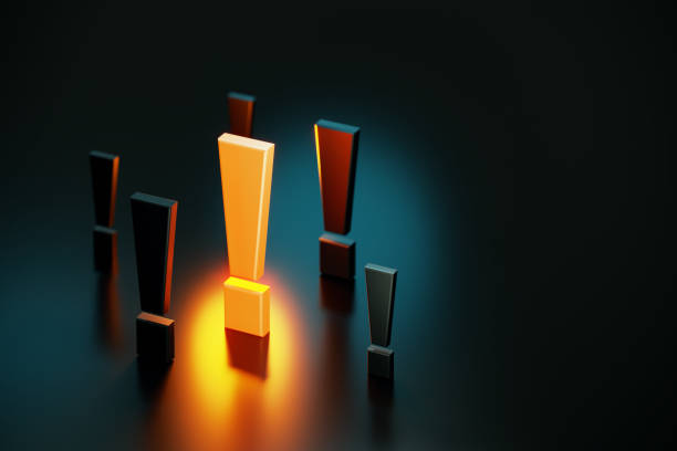 Yellow exclamation point glowing amid black exclamation points on black background. Horizontal composition with copy space. Warning concept.