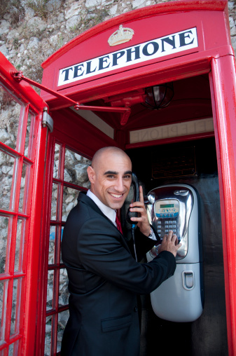 A business man using a british public phone.