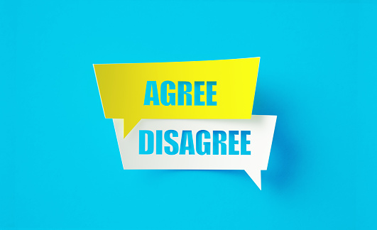 Agree disagree written cut out yellow and white speech bubbles sitting on blue background. Horizontal composition with copy space.