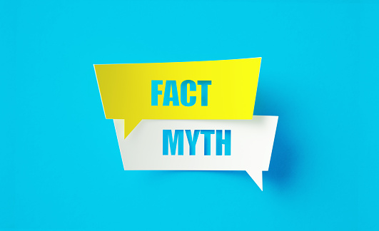 Fact myth written cut out yellow and white speech bubbles sitting on blue background. Horizontal composition with copy space.
