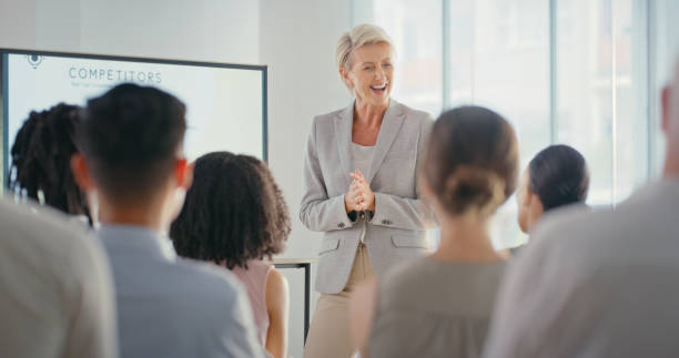 istock Leadership, training and coaching with mature mentor sharing goal and vision at a presentation. Happy leader discuss strategy and target with diverse crowd of employee, excited about mission success 1423033446